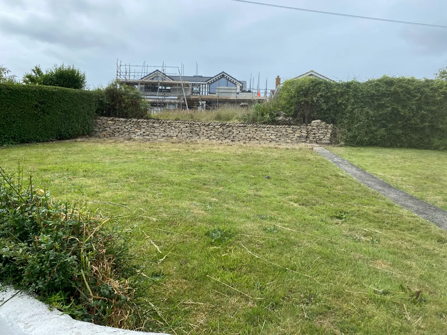 Finished stone wall running along a lawn in Cornwall