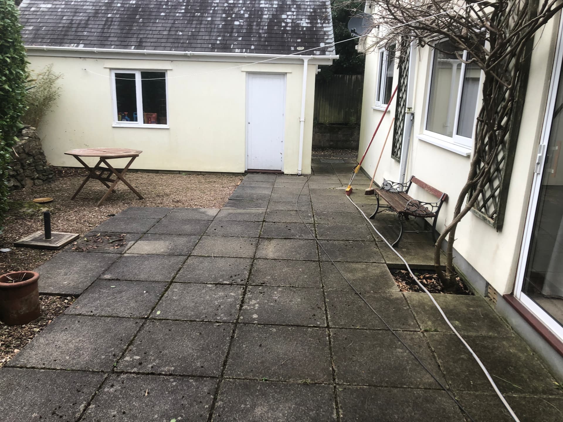 Patio paving covered in moss and algae before pressure washing in South East Cornwall